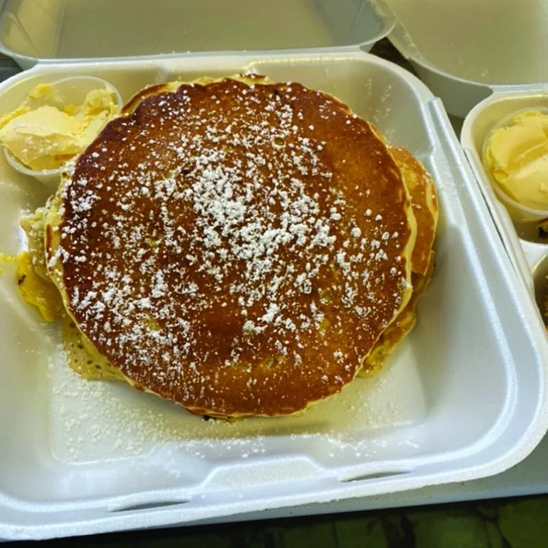 Stack of pancakes with powdered sugar and butter
